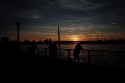 Silhouette people on beach against sky during sunset