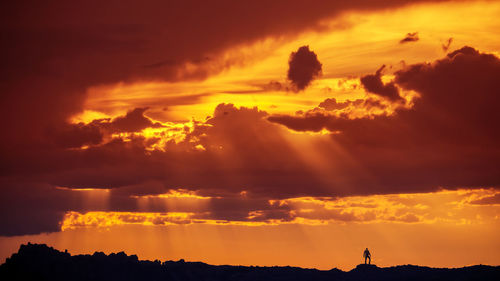 Silhouette of man standing in desert landscape under incredible sunset