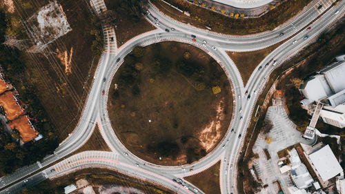 Top down aerial view of a traffic roundabout on a main road in an urban area.