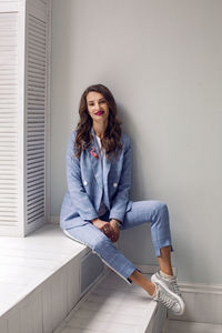 Portrait of young woman sitting on wall