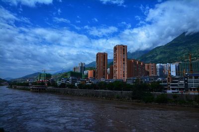 River amidst buildings in city against sky