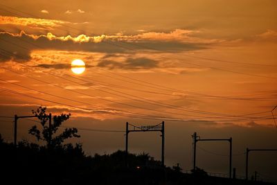 Silhouette electricity pylon against sky during sunset