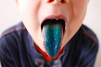 Midsection of boy showing green tongue