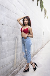 Portrait of young woman standing against wall