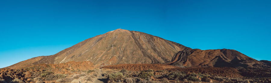 Scenic view of rocky mountains against clear blue sky