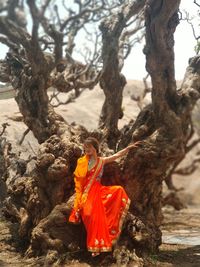 Woman wearing sari while sitting on tree trunk at desert