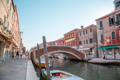 Bridge over canal by buildings against sky in city