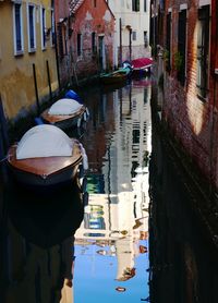 Boats moored in canal in city