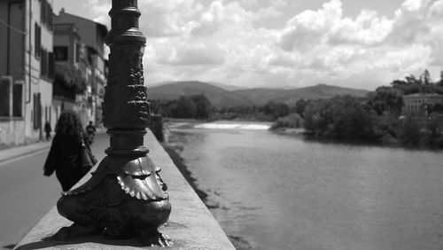 Sculpture by river in city against sky