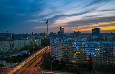 Illuminated buildings in city against sky during sunset