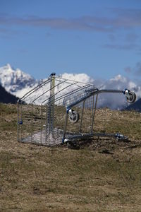Close-up of shopping cart on field against sky