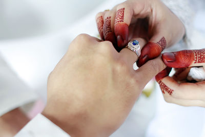 Cropped image of woman putting ring on man hand during wedding