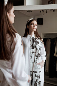 Side view of girl standing by mirror at home