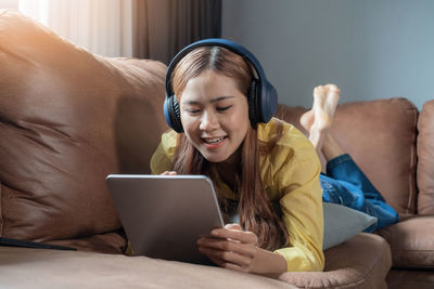 Young woman using laptop while sitting on sofa at home