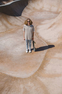 Young man standing with skateboard at sports ramp on sunny day