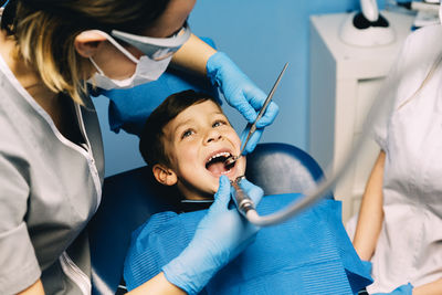 Dentist operating cheerful boy in medical clinic