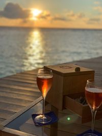 Wineglass on table against sea during sunset