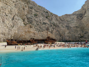 People at beach against rock formation