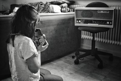 High angle view of teenager holding camera photographing vintage radio