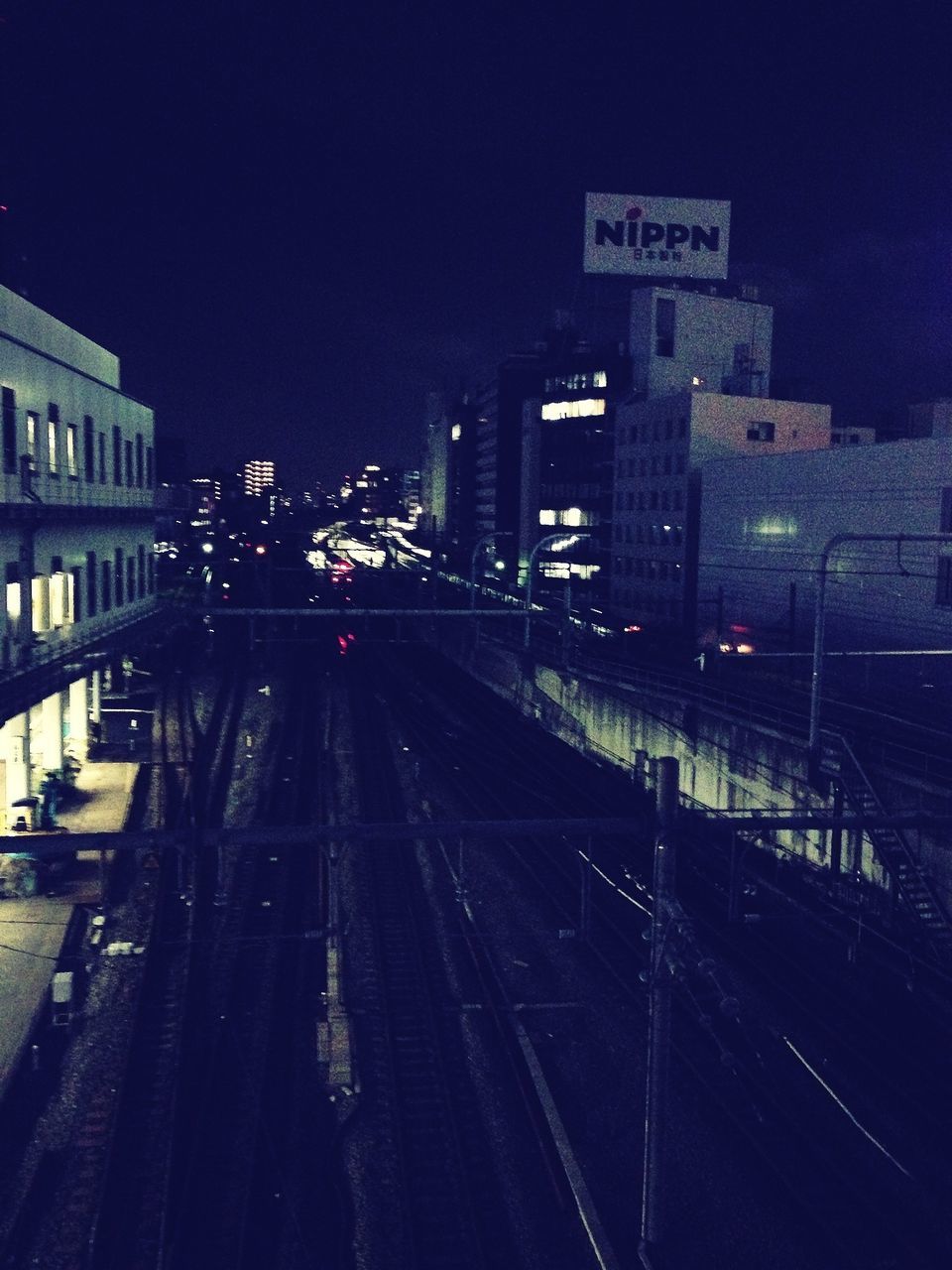 illuminated, night, transportation, building exterior, architecture, city, built structure, clear sky, the way forward, railroad track, street light, road, street, high angle view, diminishing perspective, city life, road marking, mode of transport, copy space, sky