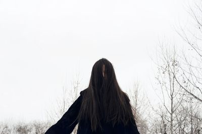  woman with long hair standing against clear sky in winter