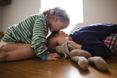 Side view of girl kissing brother on head at home