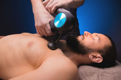 Close-up of a caucasian male pectoral muscle percussion massager working out in a professional