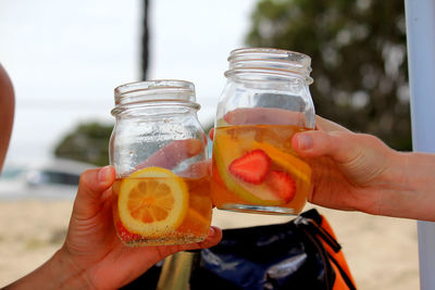 Cropped image of people toasting cocktail drink at beach