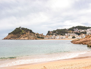 Scenic view of sea by buildings against sky