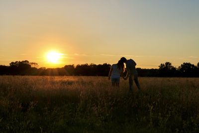 Couple on field against sky during sunset