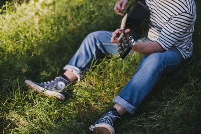 Low section of man playing guitar on grass
