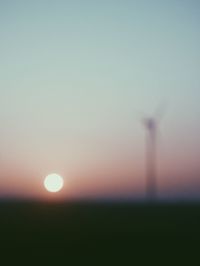 Defocused image of silhouette field against clear sky during sunset