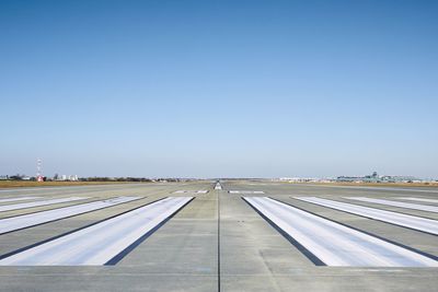 Surface level of airport runway with road marking against clear sky.