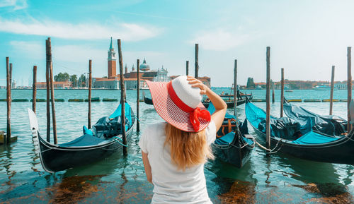 Rear view of woman standing by grand canal against sky