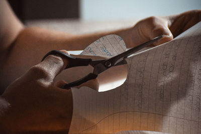 Cropped hands of man cutting paper with scissors