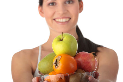 Portrait of woman holding apple against white background