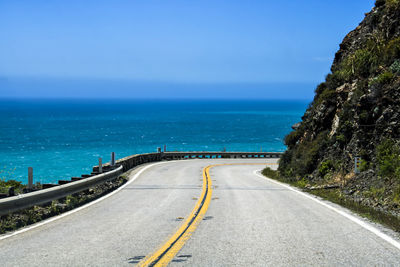 Road by sea against blue sky