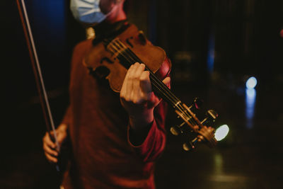 Midsection of man playing violin at music concert