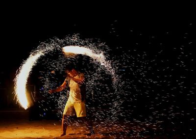 View of woman with fire crackers at night