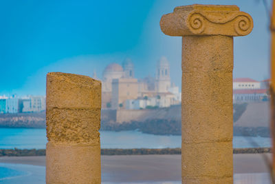 Close-up of built structure by sea against blue sky