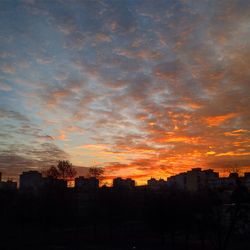 Silhouette of buildings against cloudy sky at sunset