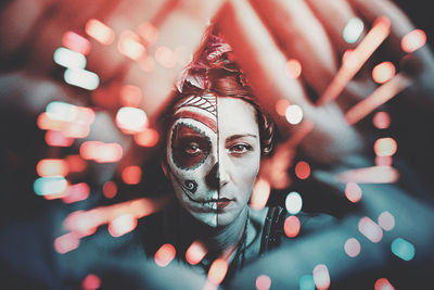 Portrait of woman with painted face against illuminated lights