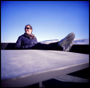 Portrait of young man sitting against clear blue sky