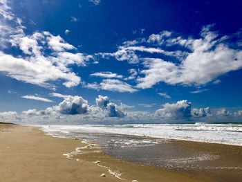 Scenic view of beach against blue sky