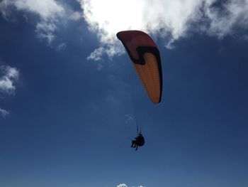 Low angle view of man paragliding against sky