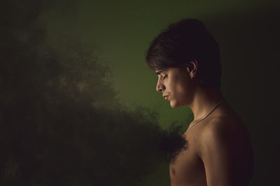 Side view of shirtless man standing against colored background