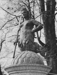Low angle view of statue against bare tree