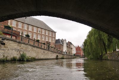 Arch bridge over river against buildings