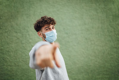 Portrait of young man standing against wall