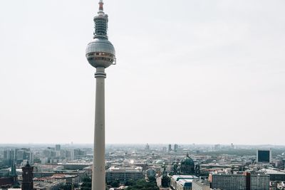 Communications tower in city against sky